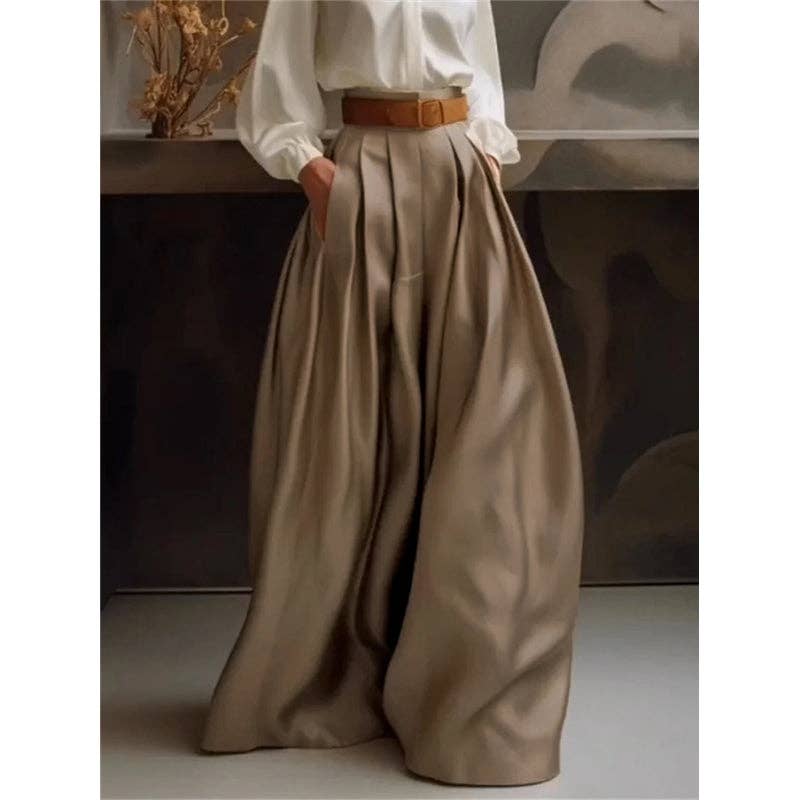 Person wearing a white blouse and beige wide-leg pants with a brown belt, standing against a neutral background.