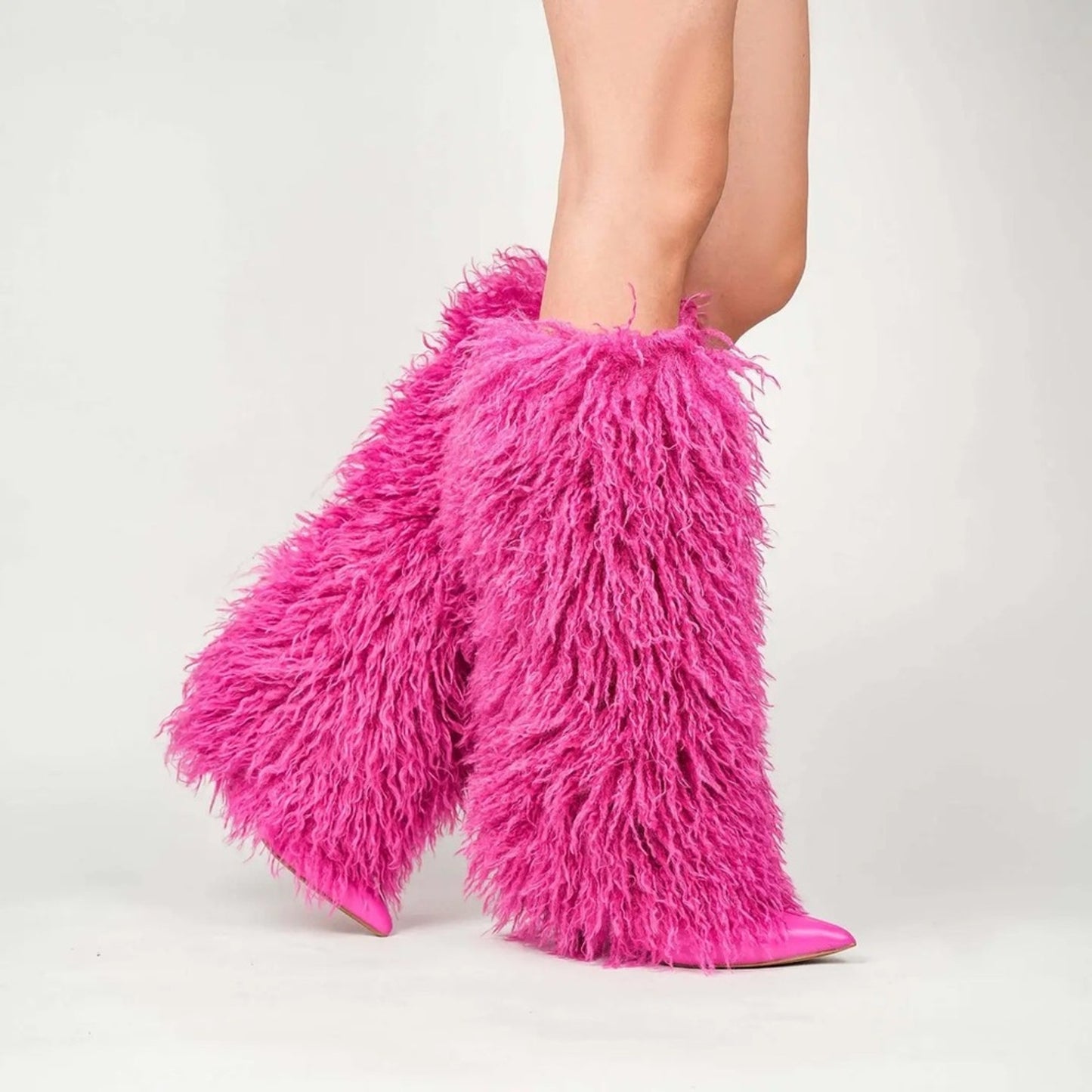 Pink furry leg warmers worn by a person on a light gray background