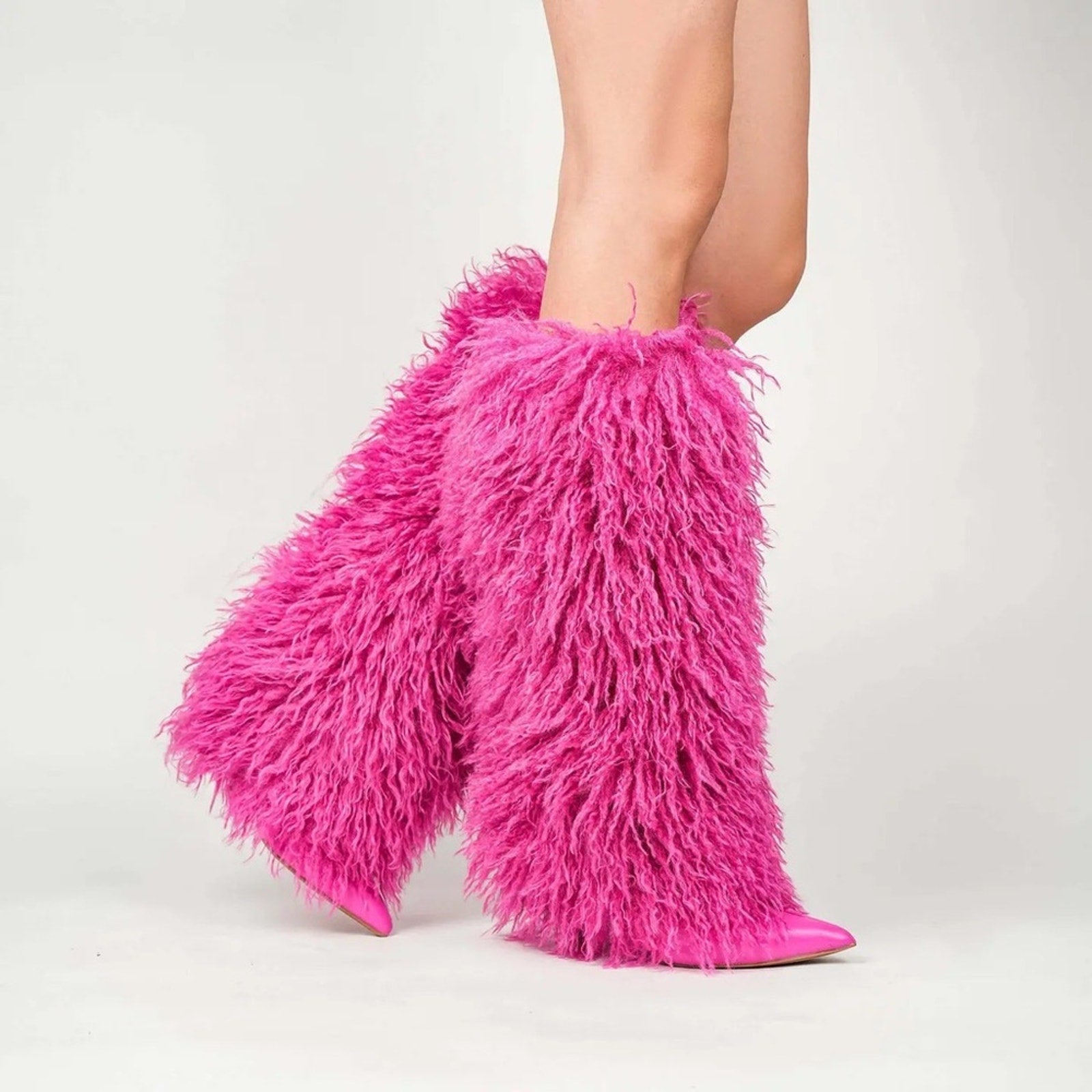 Pink furry leg warmers worn by a person on a light gray background