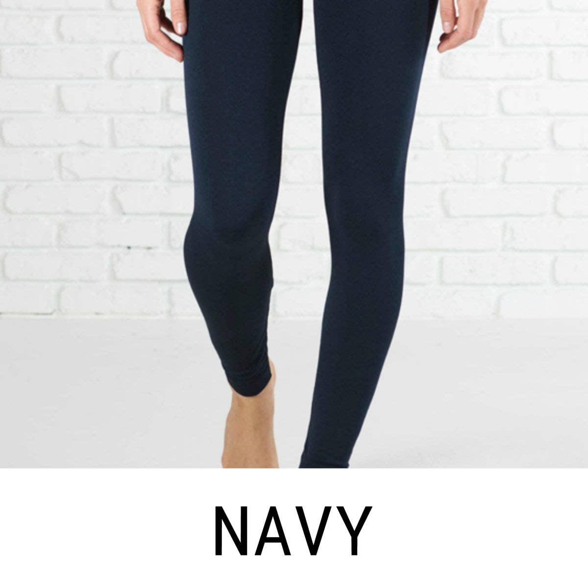 Navy leggings worn by a person against a white brick wall.