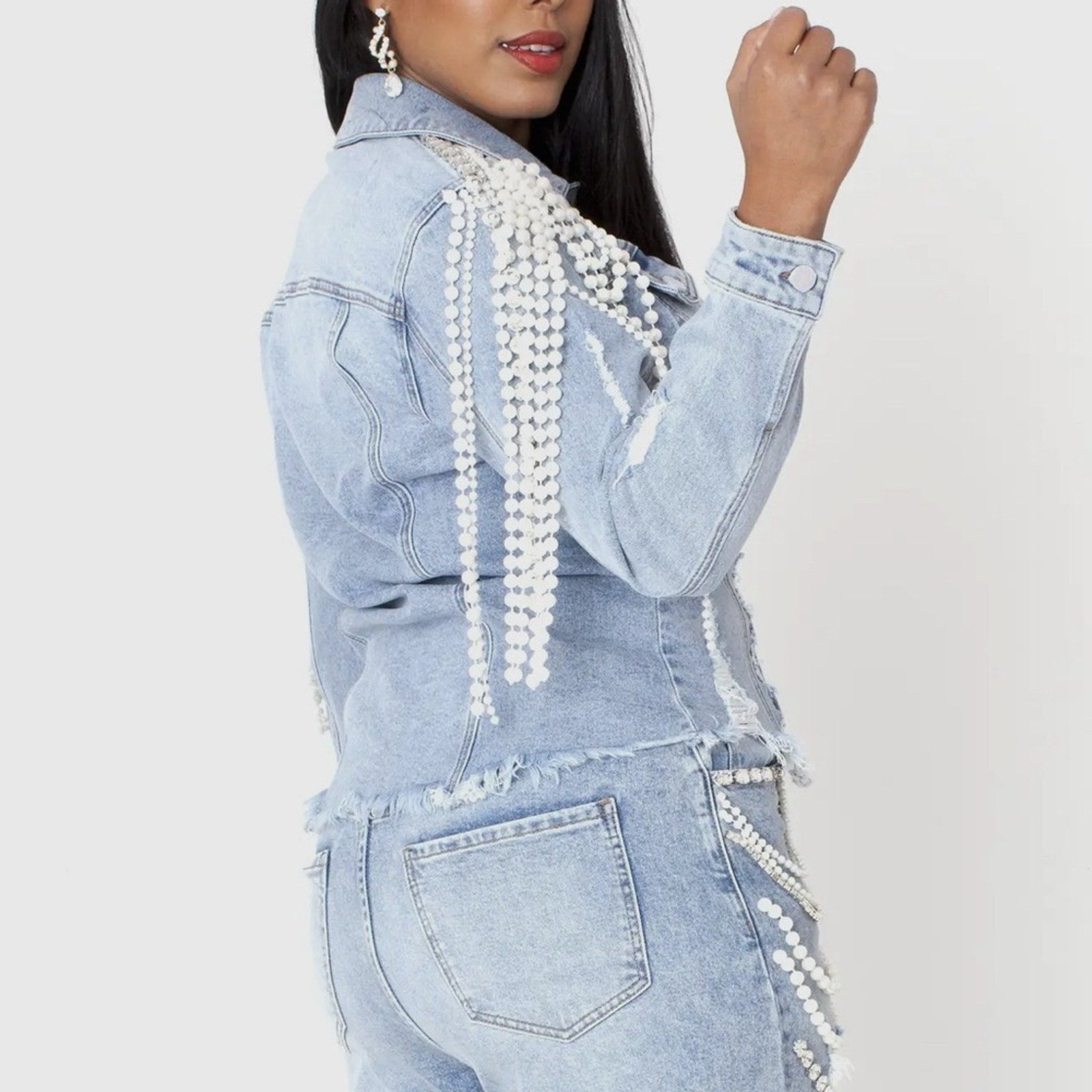 Denim outfit with pearl details on a plain background