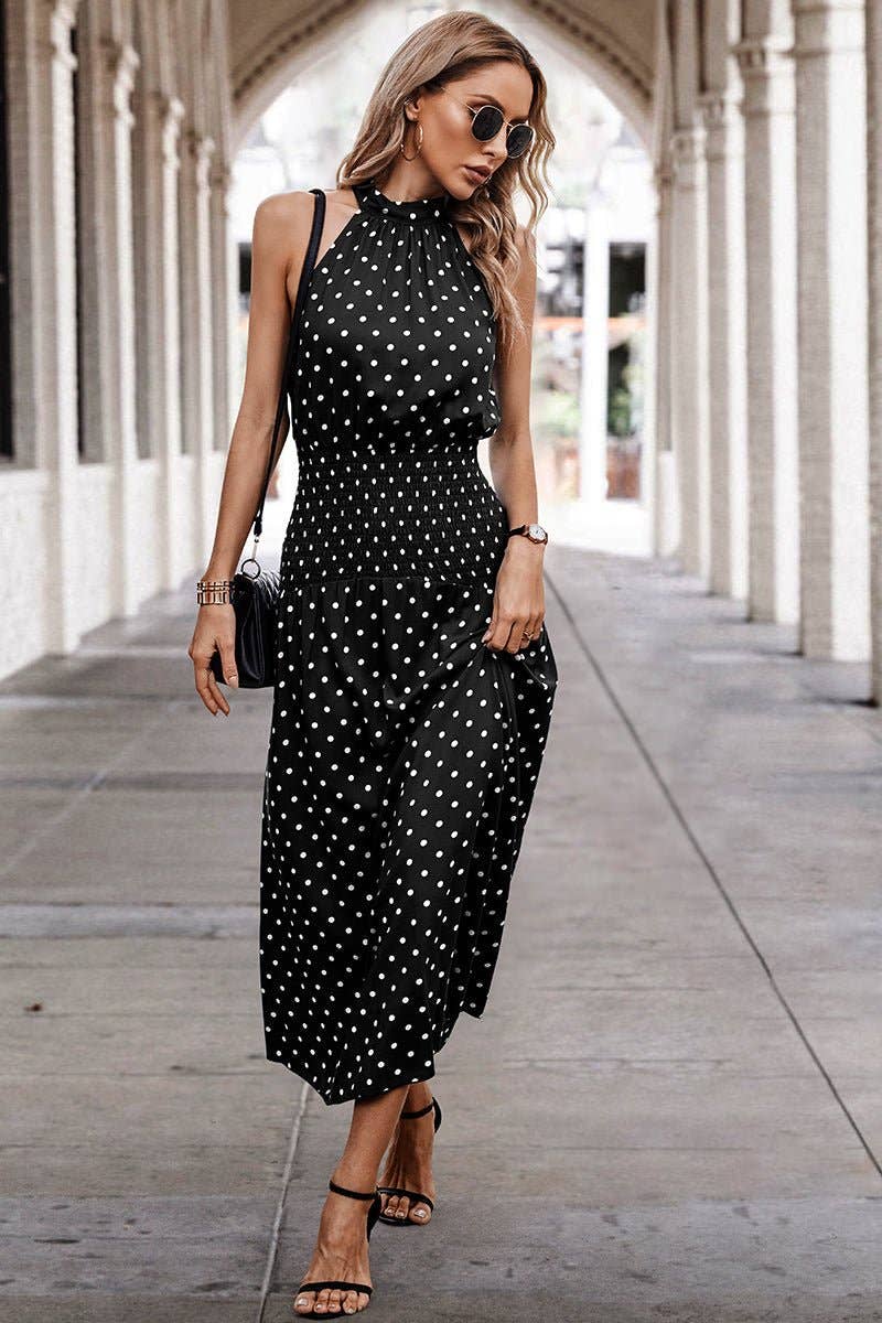 Woman wearing a black polka dot dress walking through an archway.