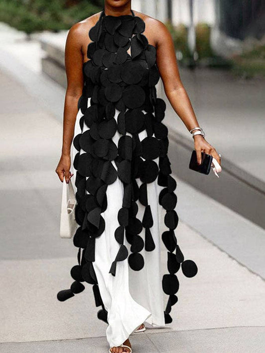 Woman wearing a black and white dress with leaf-like patterns on a city street.