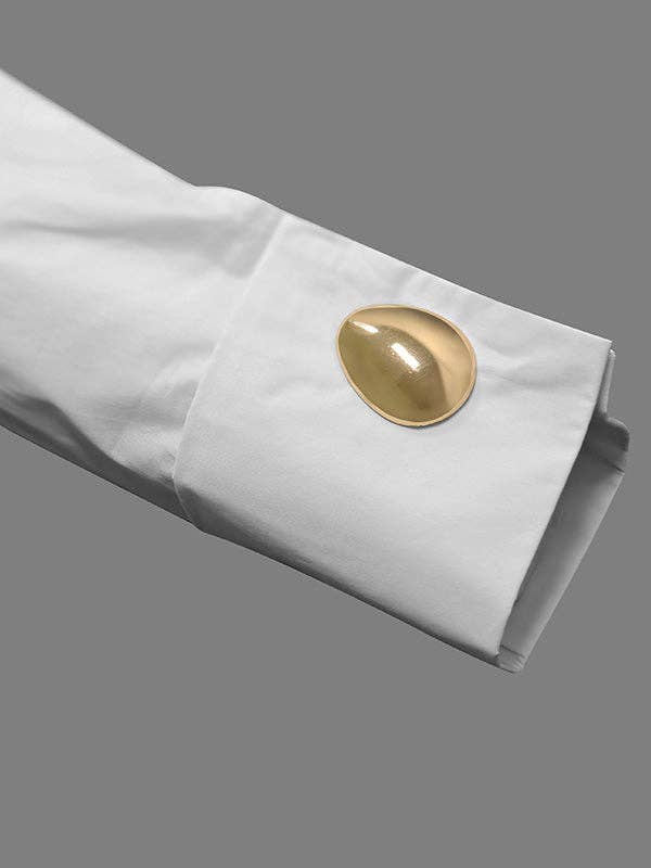 Close-up of a white cuff with a gold cufflink on a gray background