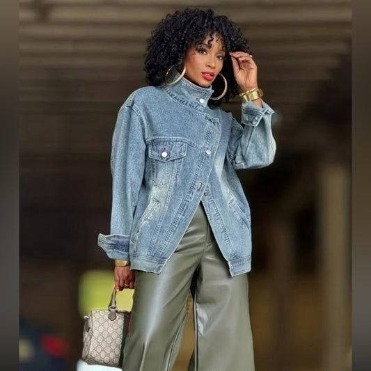 Woman wearing a denim jacket and holding a handbag against a blurred background