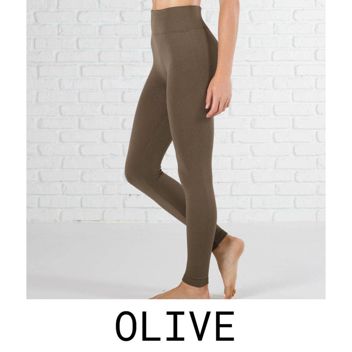 Olive green leggings worn by a person against a white brick wall.
