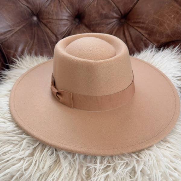 Brown fedora hat on a fluffy white surface with a brown leather couch in the background