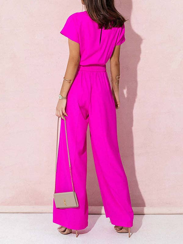 Person wearing a bright pink jumpsuit against a light pink background