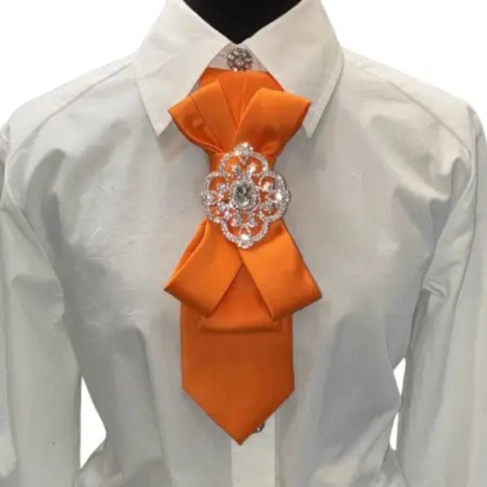 Orange tie with decorative brooch on a white shirt against a white background