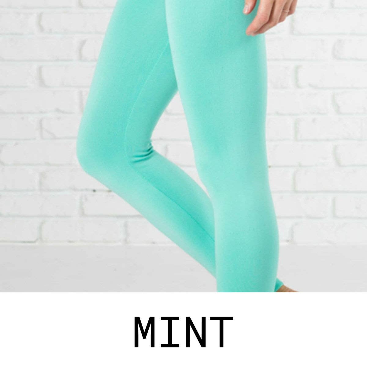 Mint green leggings worn by a person against a white brick wall.