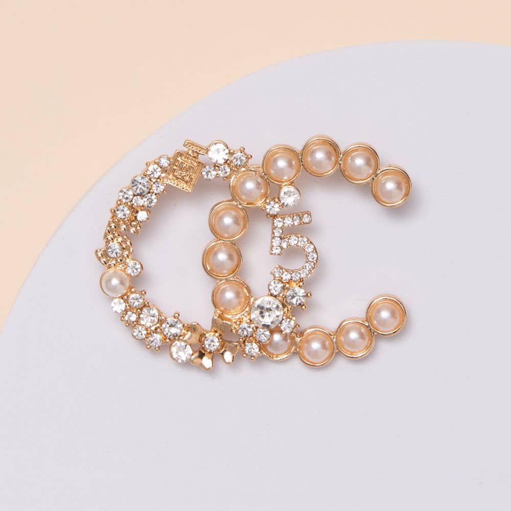 Gold bracelet with pearls and crystals on a light gray surface