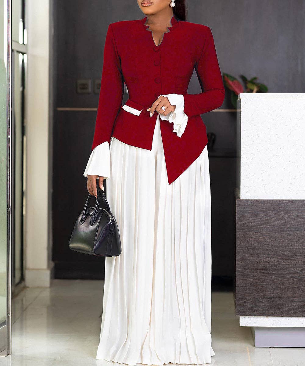 Woman wearing a red blazer and white dress holding a black handbag indoors.