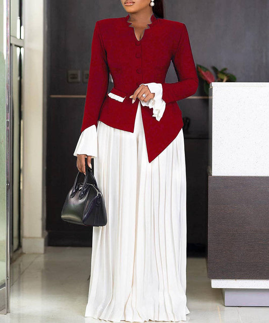 Woman wearing a red blazer and white dress holding a black handbag indoors.