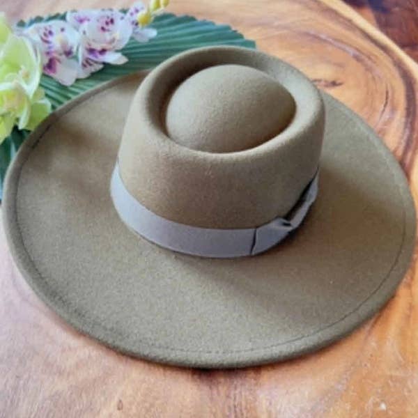 Beige wide-brimmed hat with a white band on a wooden surface with flowers in the background