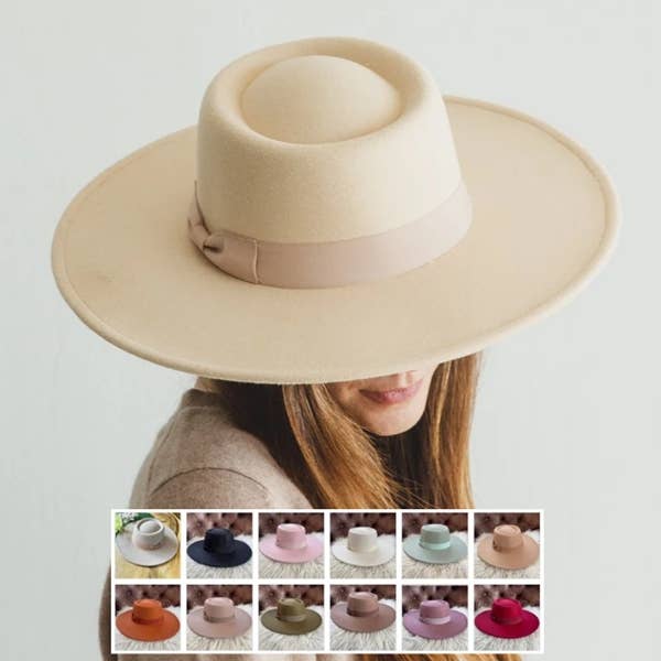 Beige wide-brimmed hat with a ribbon, shown on a person against a light gray background.
