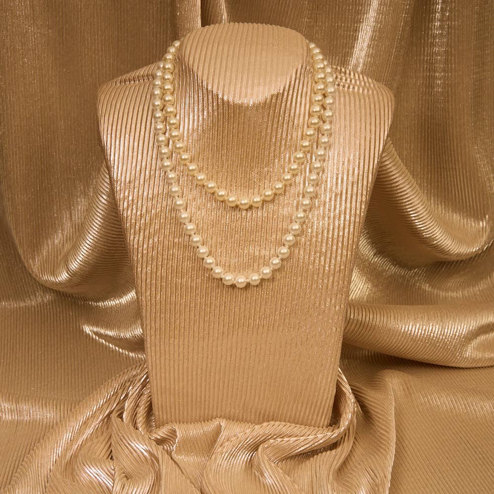 Pearl necklace on a beige mannequin against a textured beige fabric background