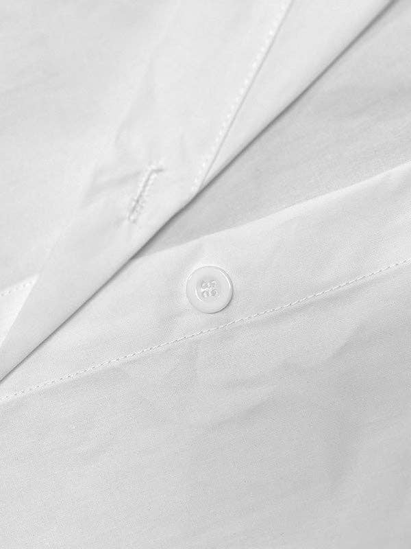 Close-up of a white shirt with a button, featuring the Tommy Hilfiger logo.