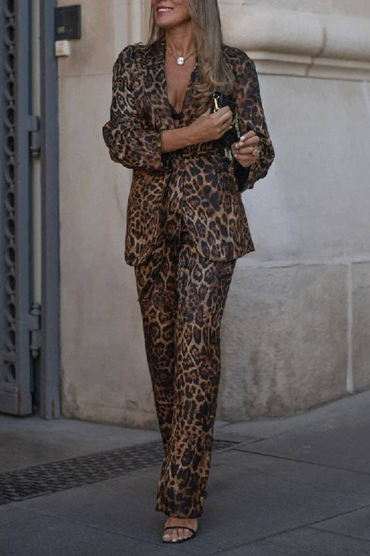 Woman wearing a leopard print suit standing against a stone wall.