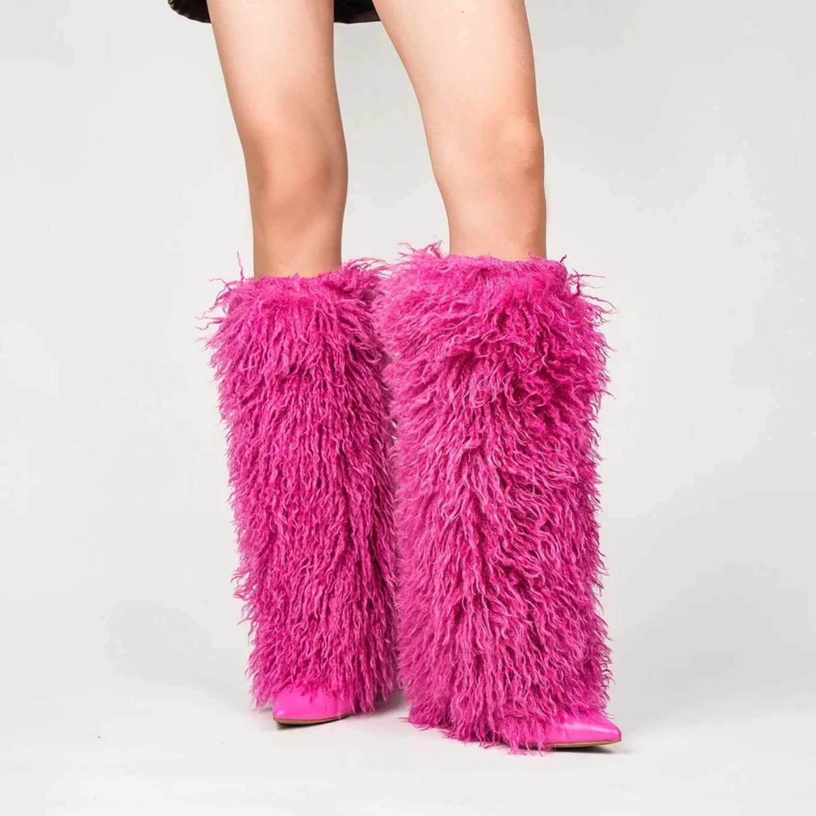 Pink furry leg warmers worn by a person on a white background