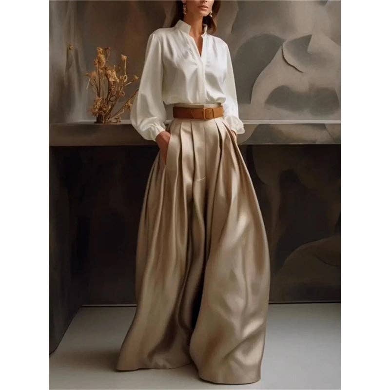 Person wearing a white blouse and beige wide-leg pants with a brown belt, standing against a neutral background.