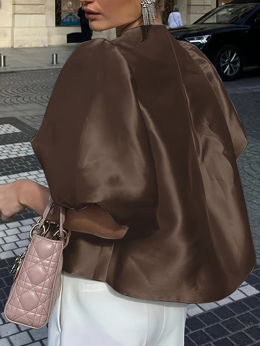 Person wearing a brown satin top with a pink handbag on a city street.