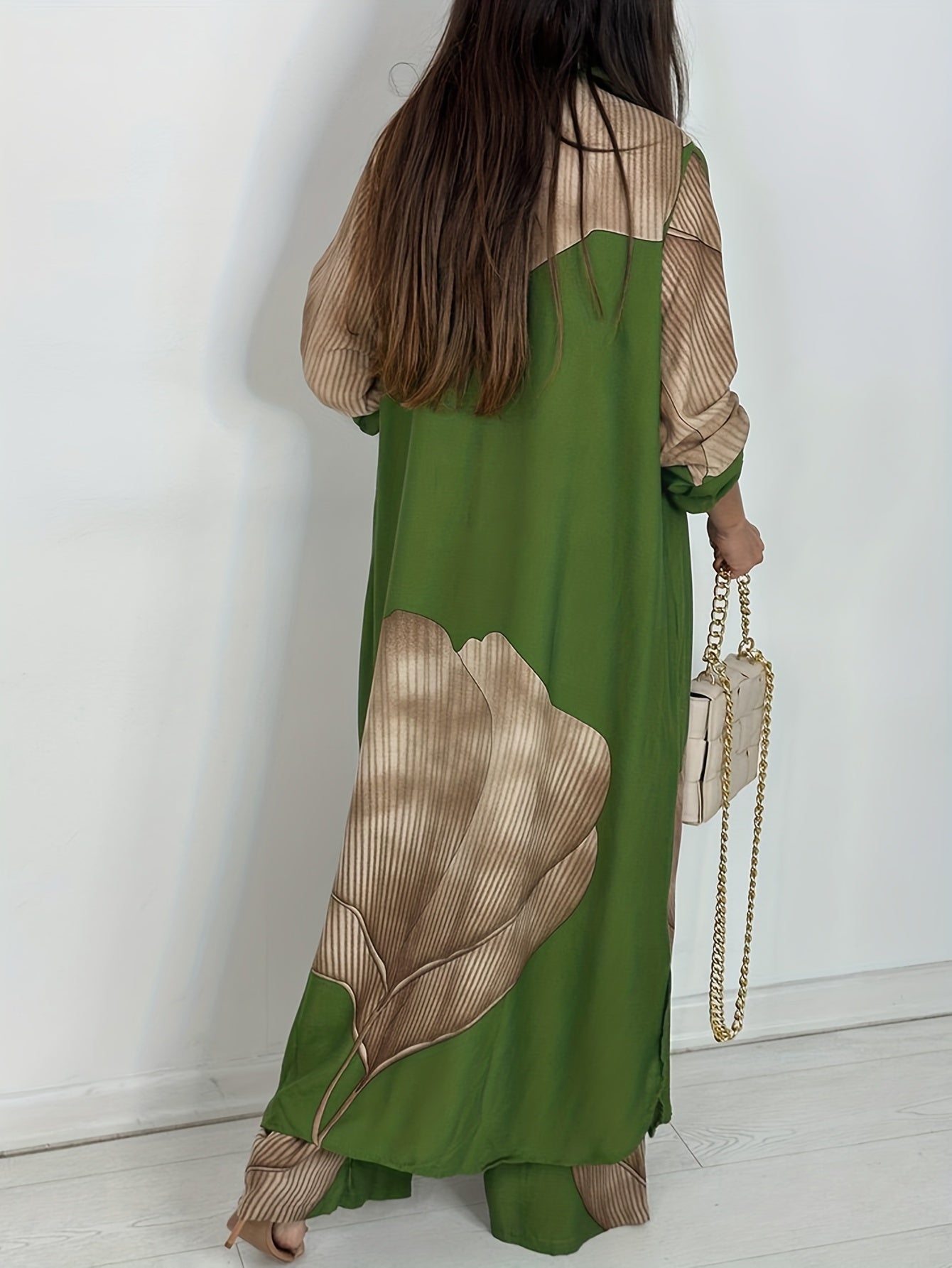 Woman wearing a green dress with brown leaf patterns, holding a beige handbag.