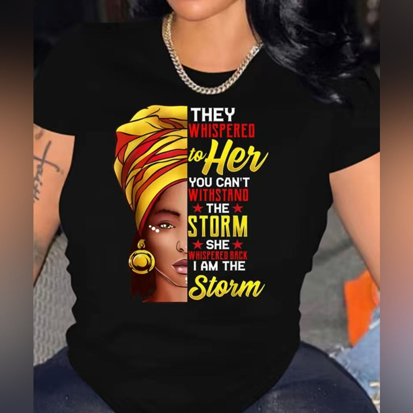 Black t-shirt with a graphic of a woman with a yellow headscarf and text, worn by a person.