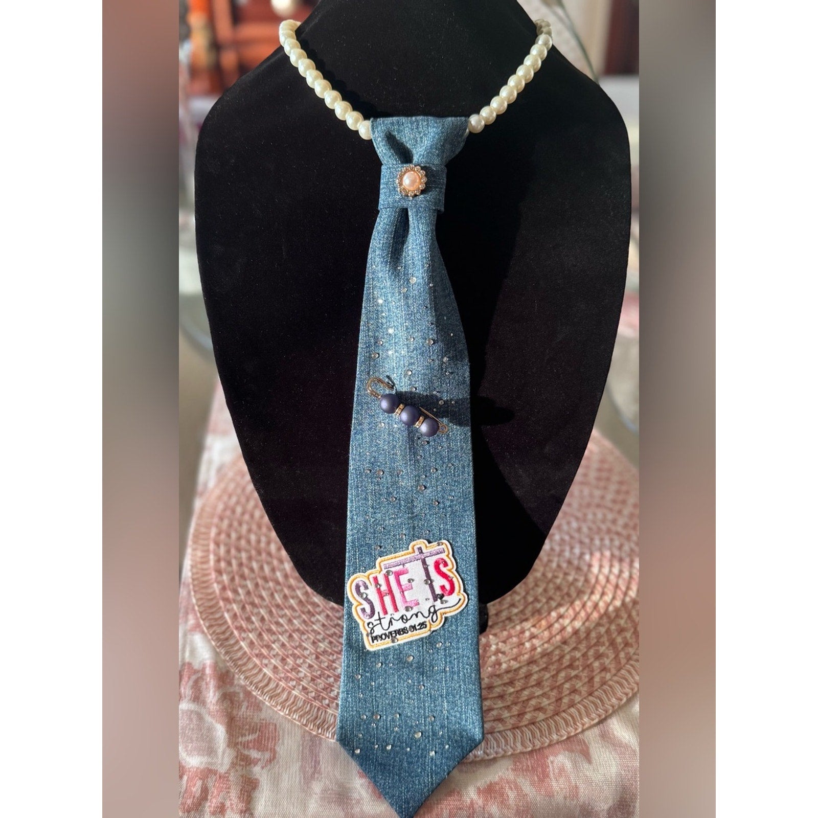 Blue denim tie with a logo on a black mannequin