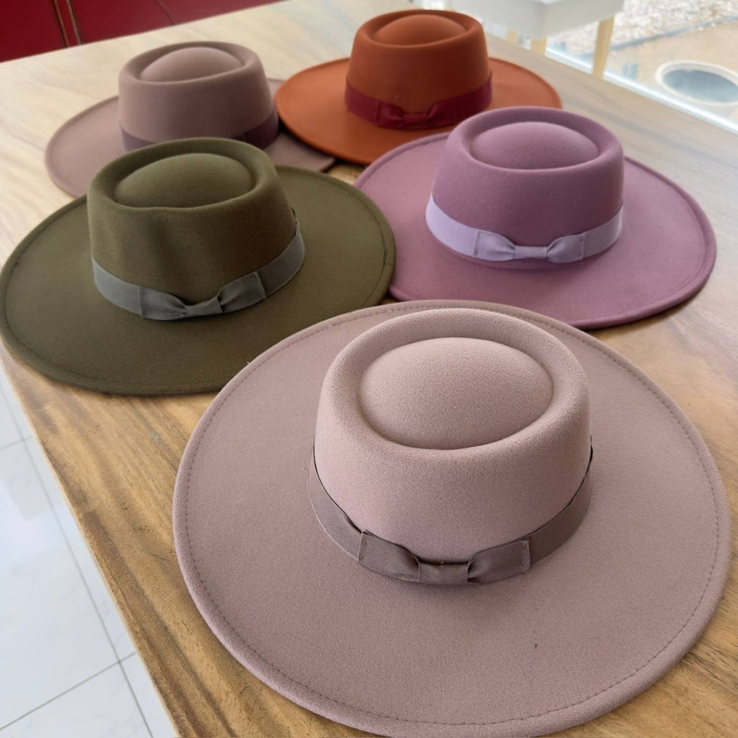 Five hats in different colors arranged on a wooden surface.