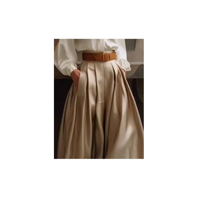 Person wearing a white blouse and beige skirt with a brown belt on a plain background
