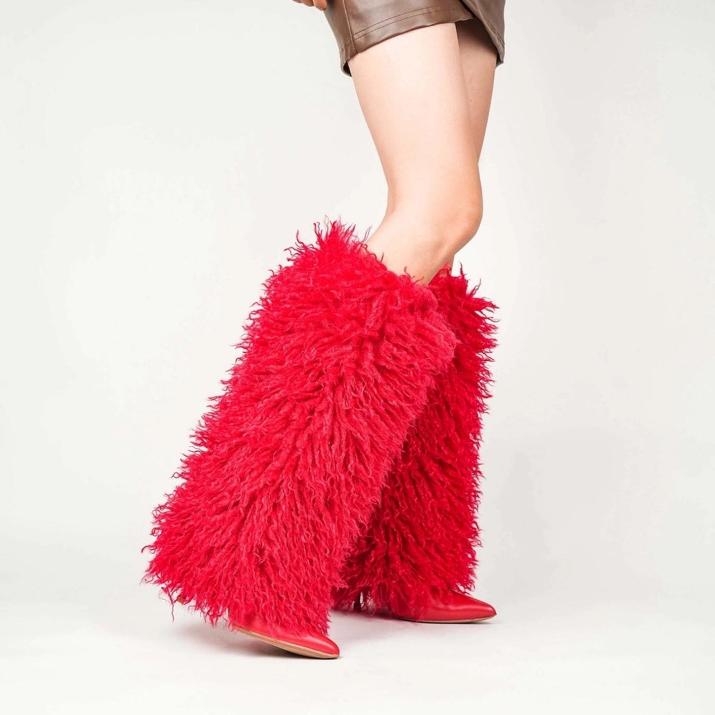 Red furry leg warmers worn by a person on a light gray background