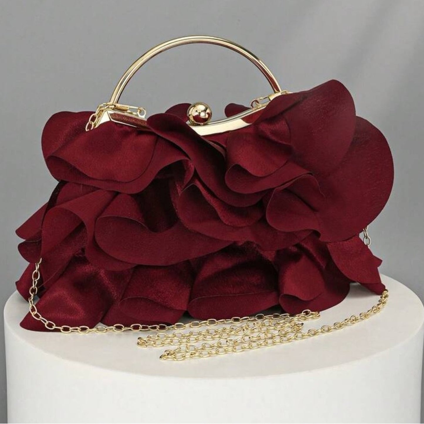 Red floral handbag with gold chain on a gray background