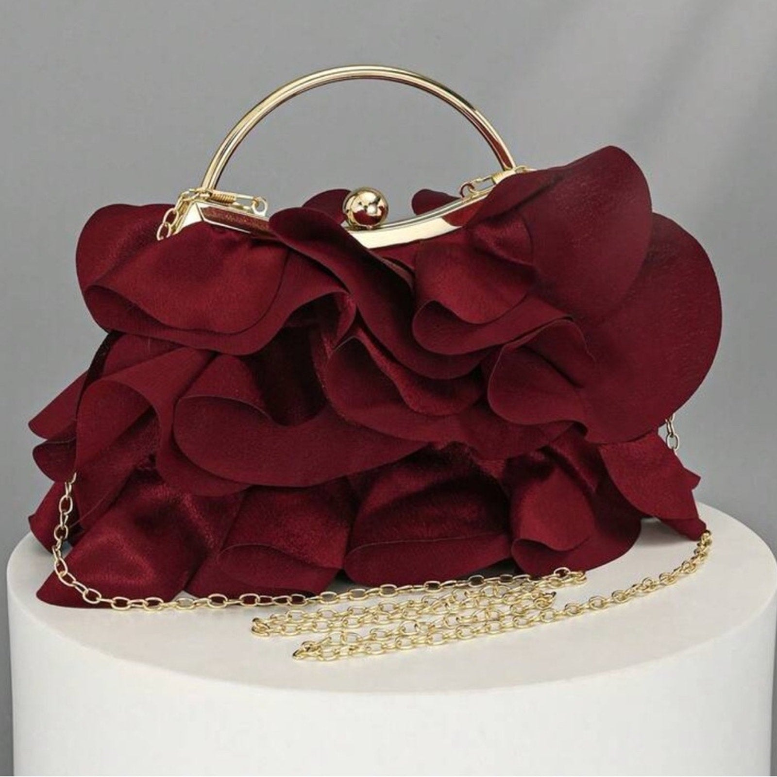 Red floral handbag with gold chain on a gray background