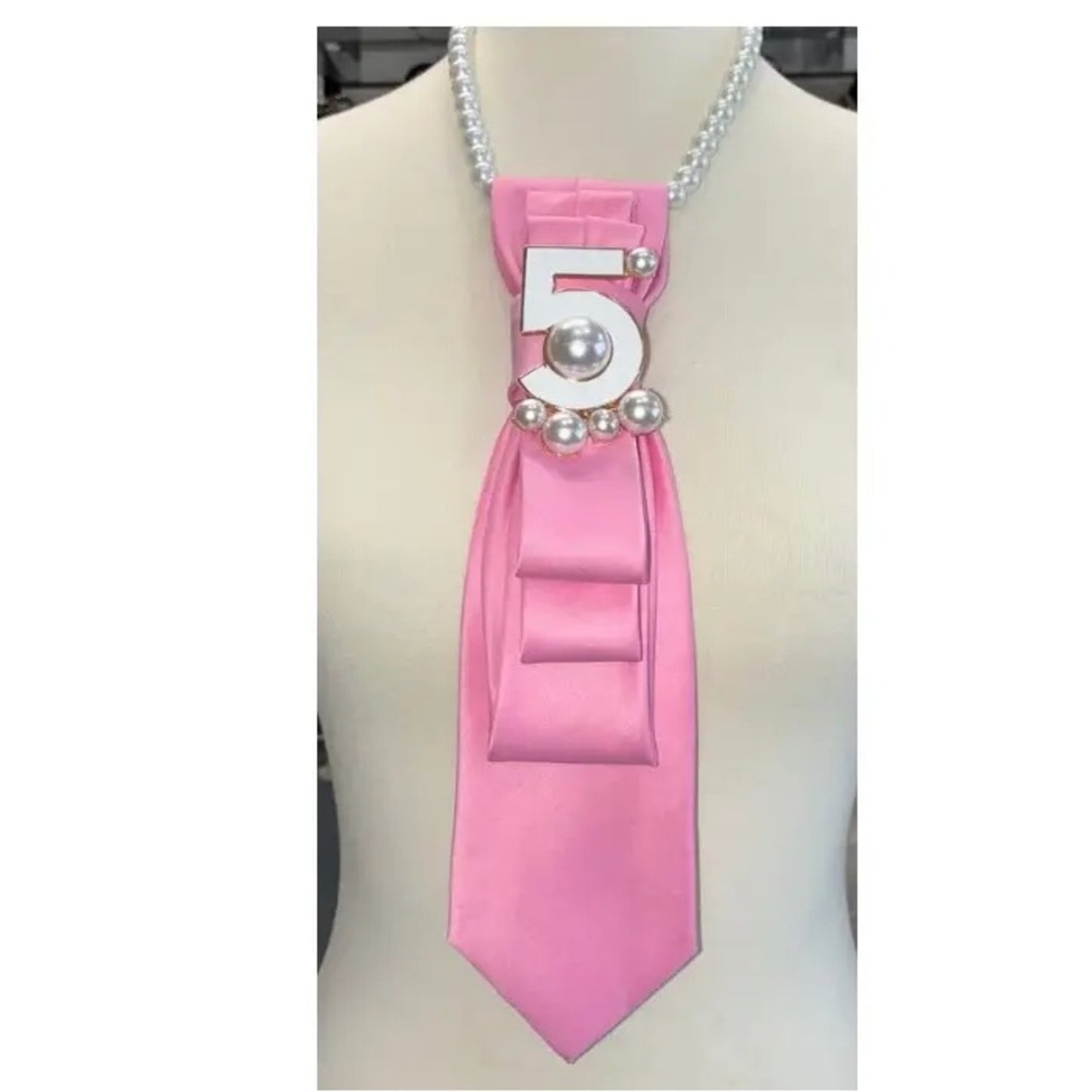 Pink ribbon with number 5 and pearls on a mannequin