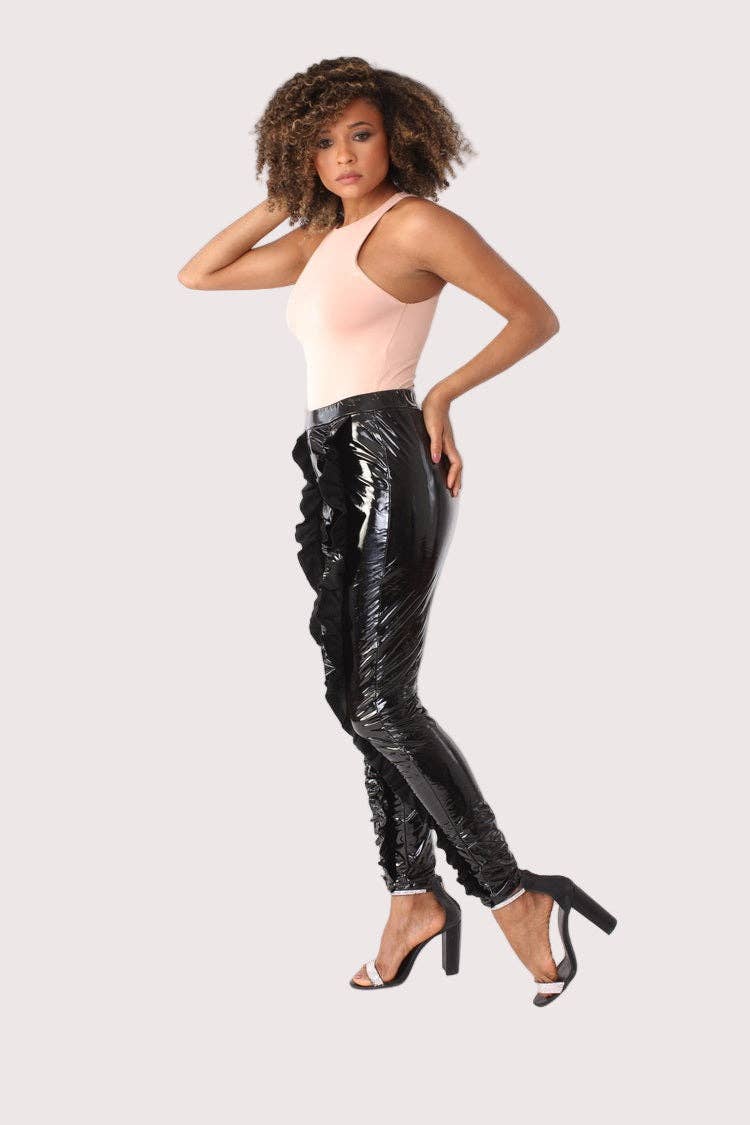 Woman wearing a pink top and black shiny pants on a white background