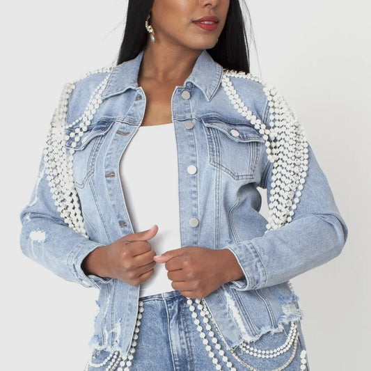 Denim jacket with pearl embellishments worn by a model on a plain background