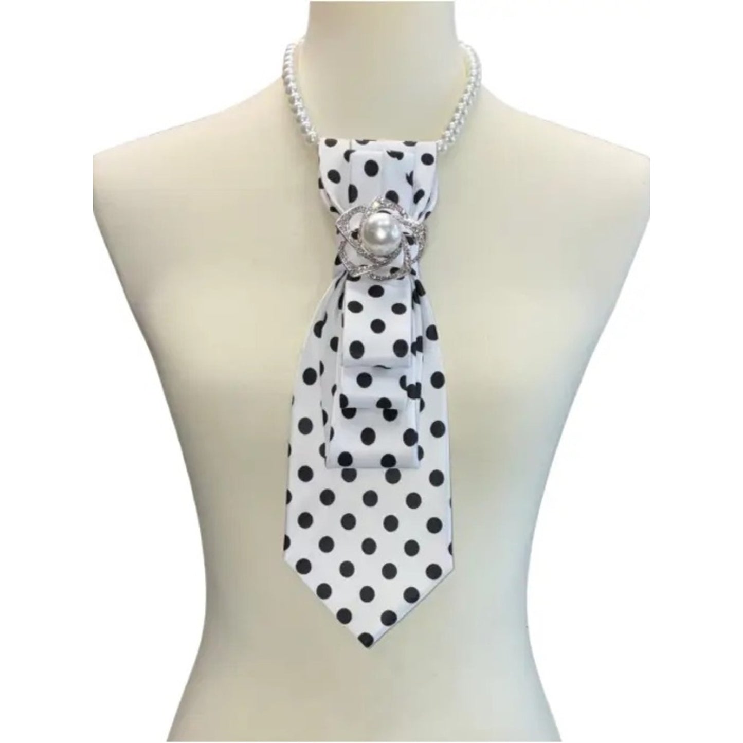 Mannequin wearing a black and white polka dot scarf with a pearl brooch on a white background