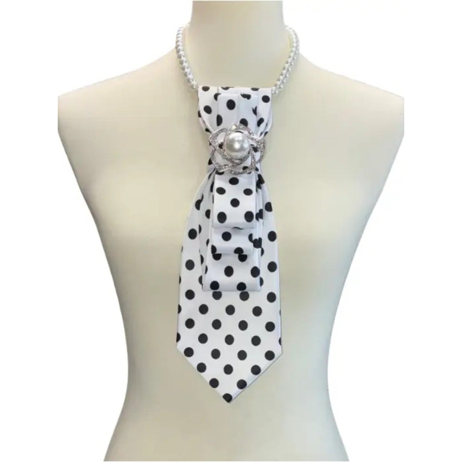 Mannequin wearing a black and white polka dot scarf with a pearl brooch on a white background