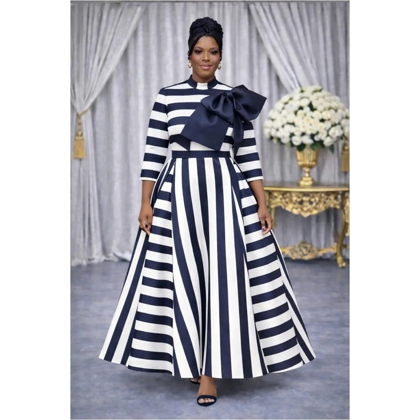 Woman wearing a black and white striped dress with a large bow in a decorated room.