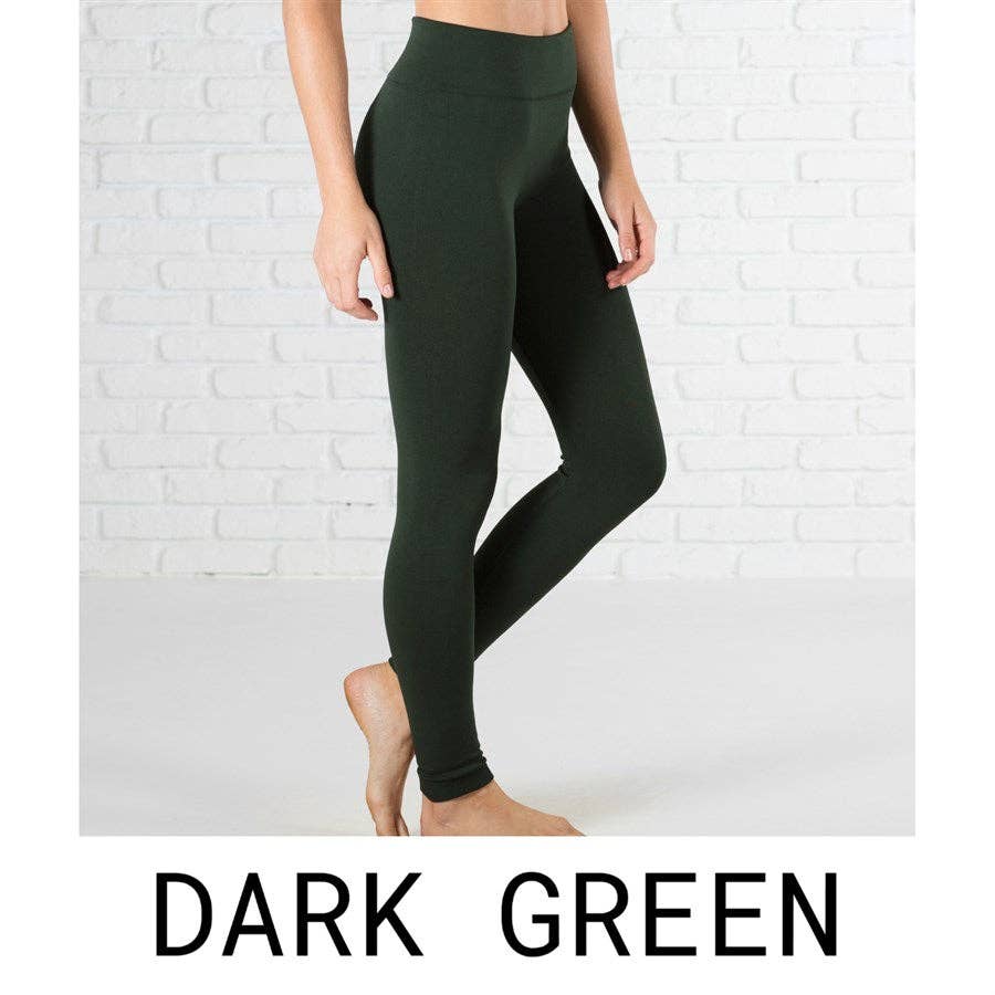 Dark green leggings worn by a person against a white brick wall.