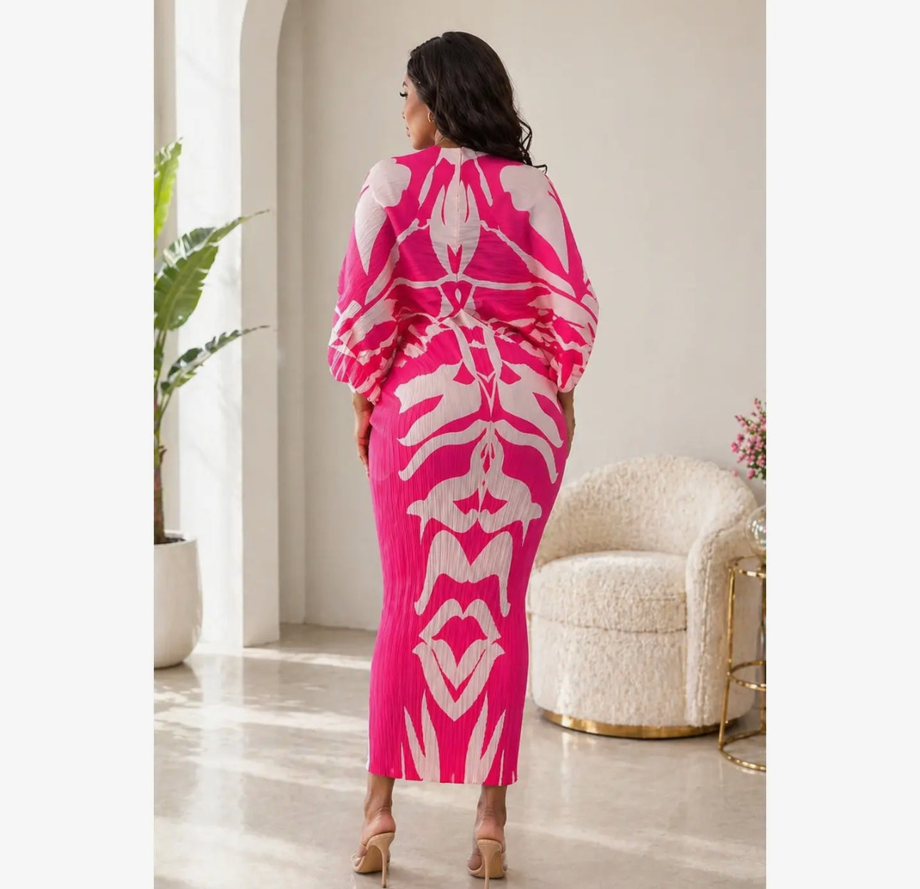 Woman wearing a bright pink and white patterned outfit in a stylish room.