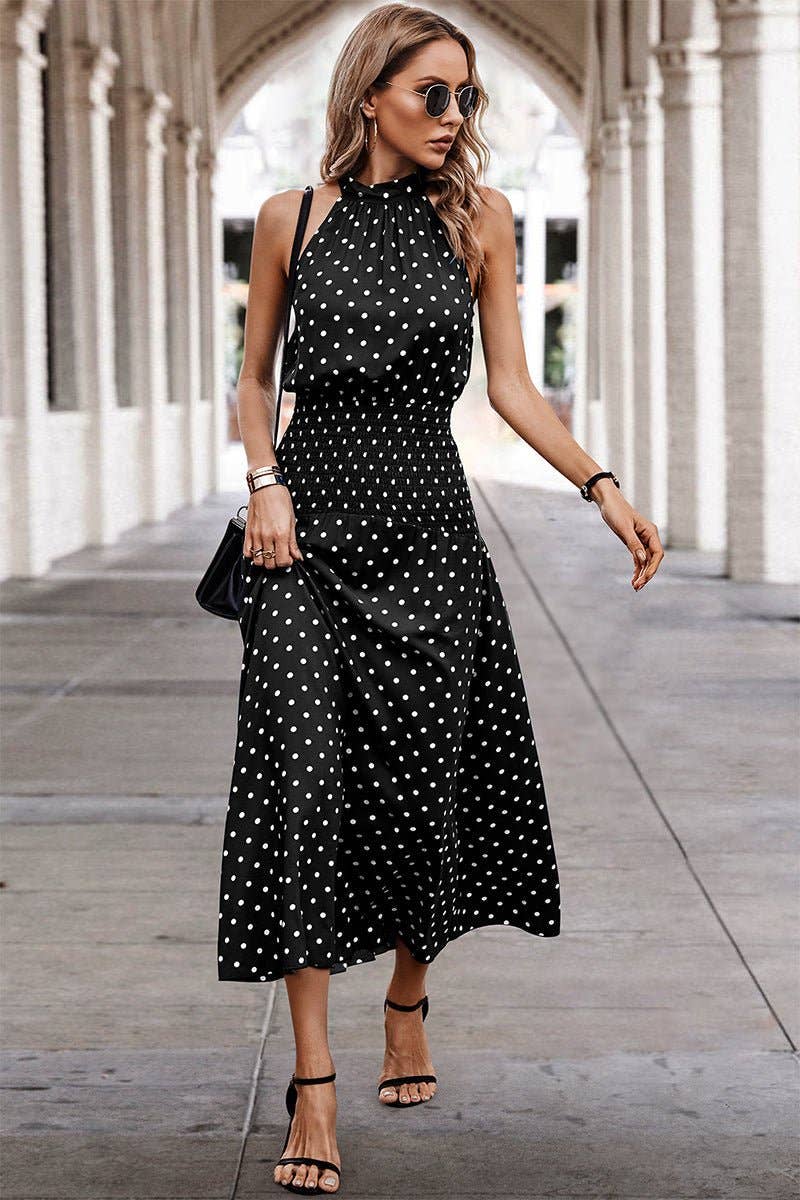 Woman wearing a black polka dot dress walking under an archway.