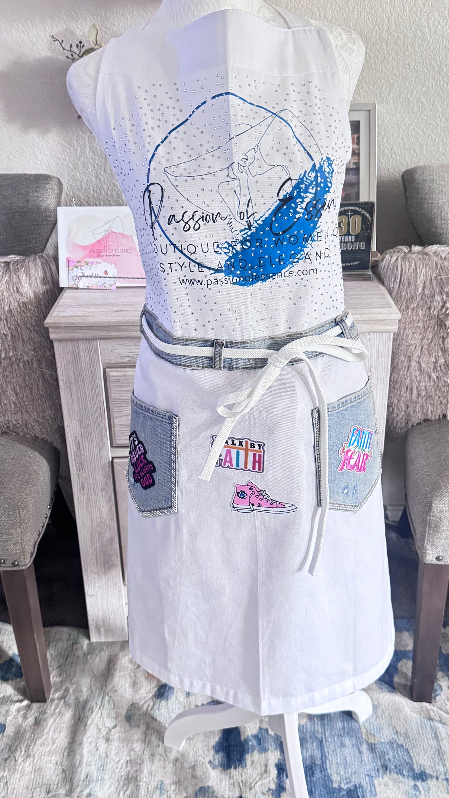 White dress with colorful patches on a mannequin in a room setting.