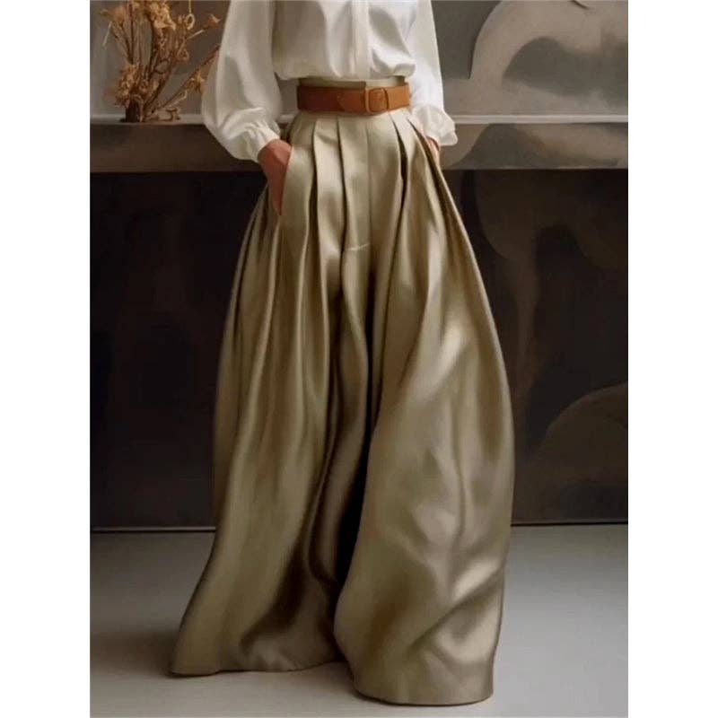 Person wearing a white shirt and beige wide-leg pants with a brown belt, standing against a neutral background.