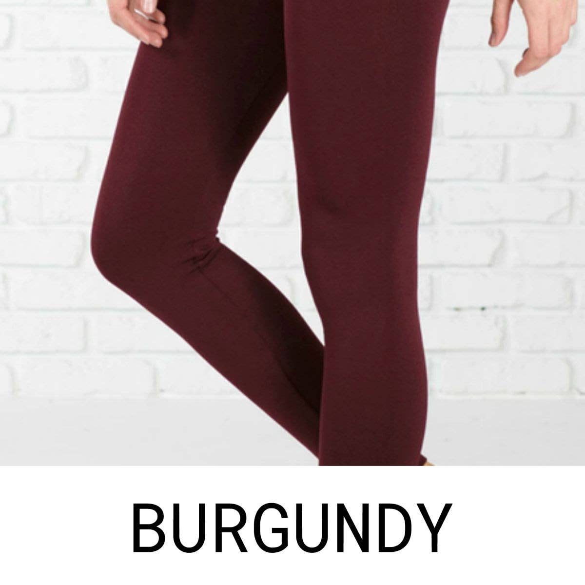 Burgundy leggings worn by a person against a white brick wall.