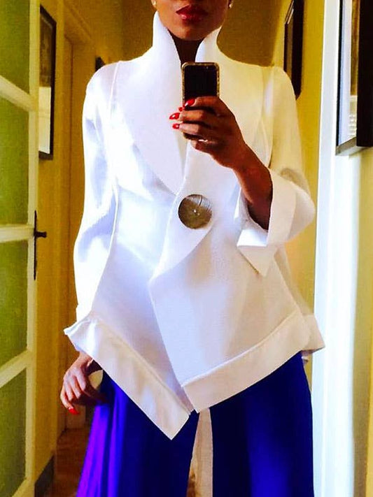Person wearing a white top with a large button and blue pants, taking a mirror selfie.