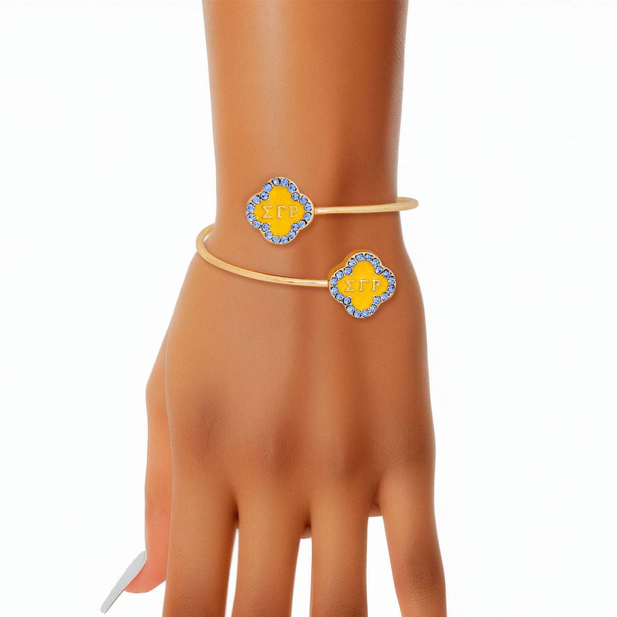 Gold bracelet with yellow and blue accents on a mannequin hand against a white background