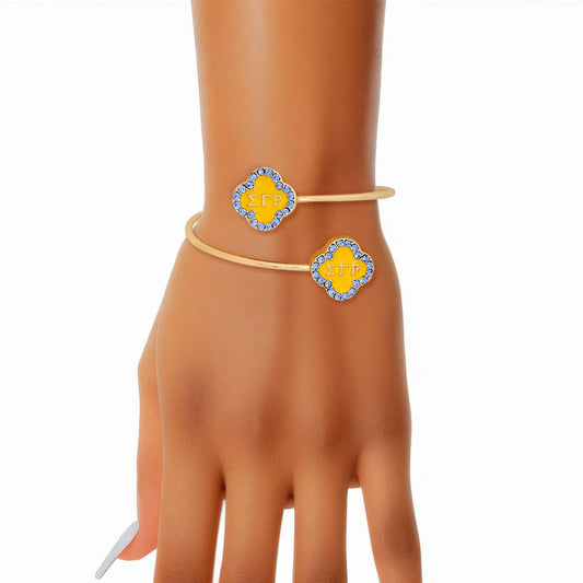 Gold bracelet with yellow and blue accents on a mannequin hand against a white background