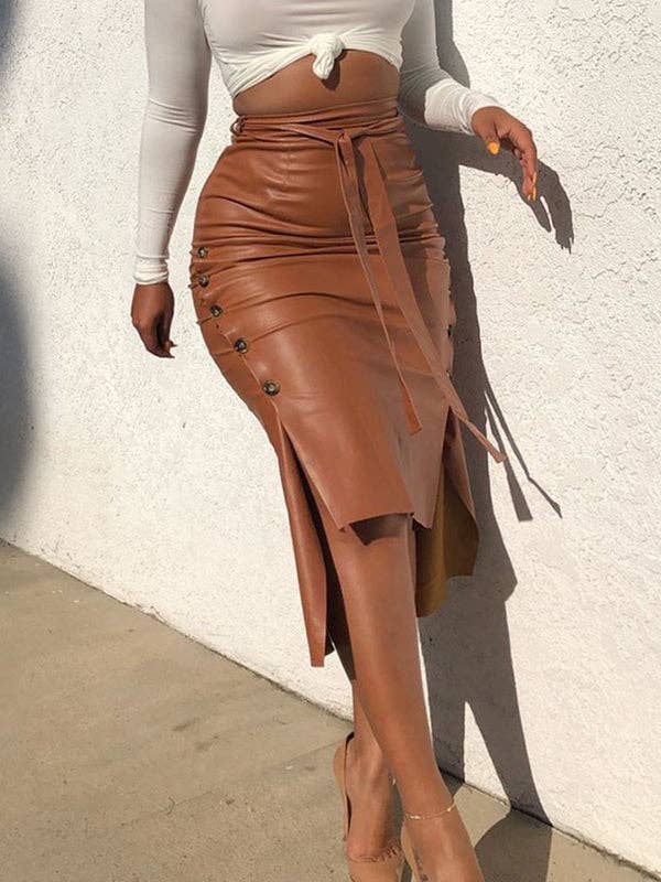 Person wearing a brown leather skirt with a white top against a white wall.