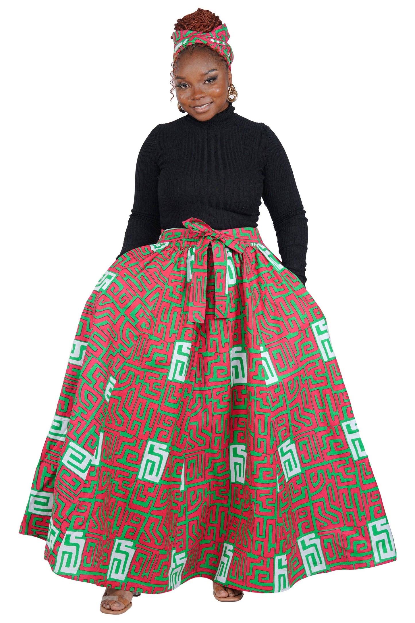 Woman wearing a black top and red and green patterned skirt on a white background